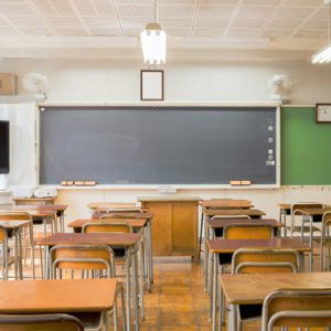 Empty desks in a classroom looking towards the chalkboard